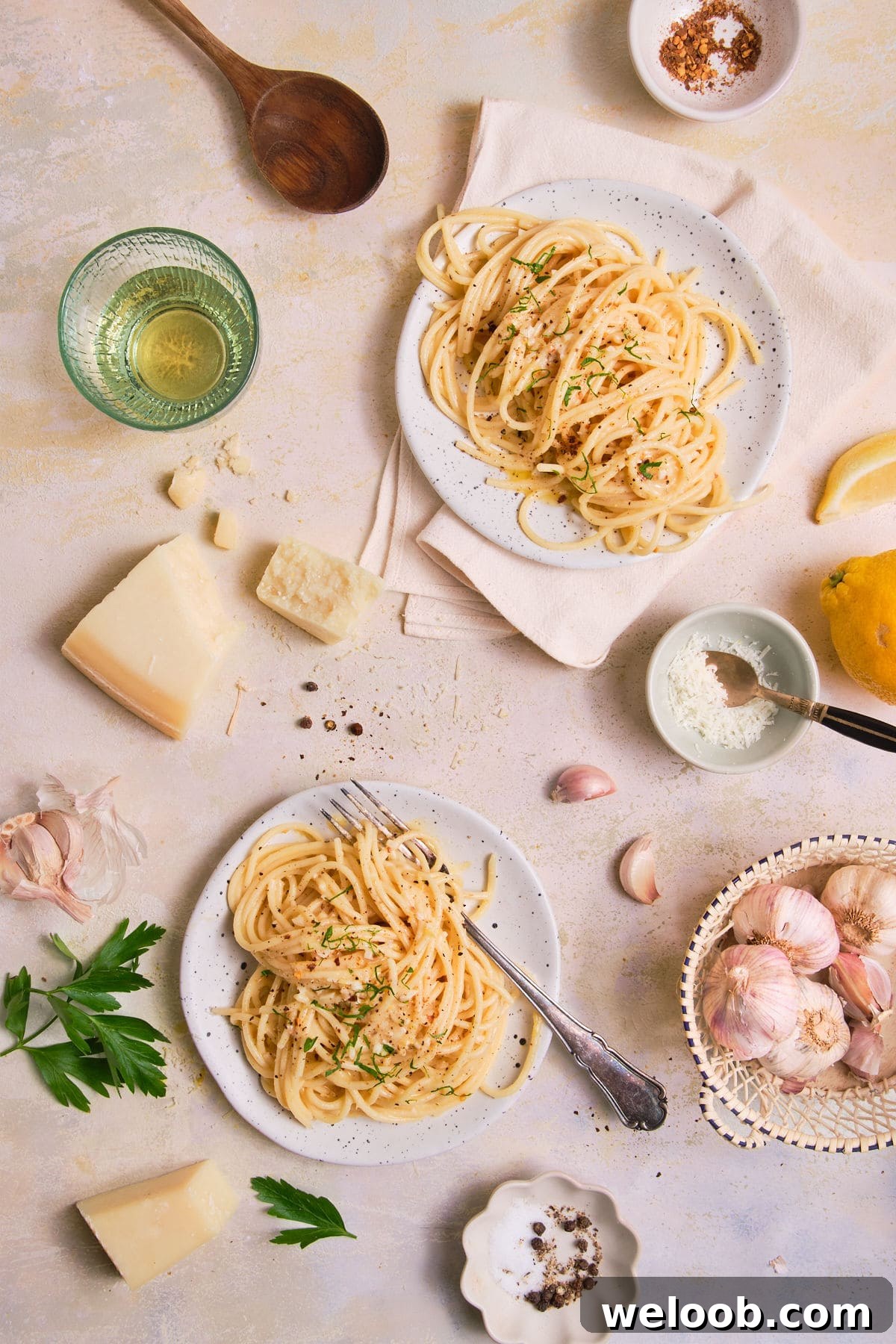 2 plates of swirled spaghetti garnished with parsley and black pepper.