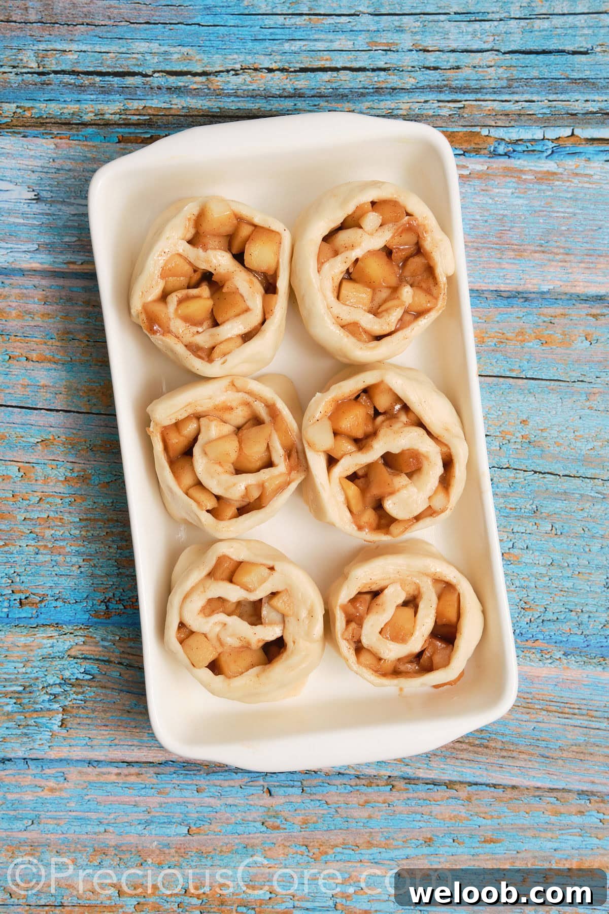 Cinnamon apple rolls placed into buttered casserole dish.