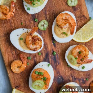 Deviled eggs with Cajun shrimp on a chopping board.