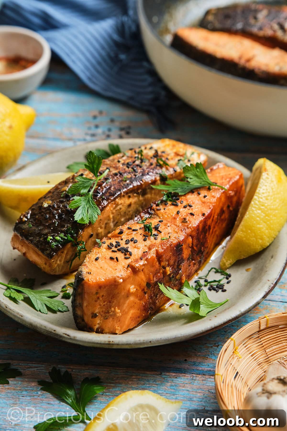 2 cooked salmon fillets garnished with black sesame seeds.