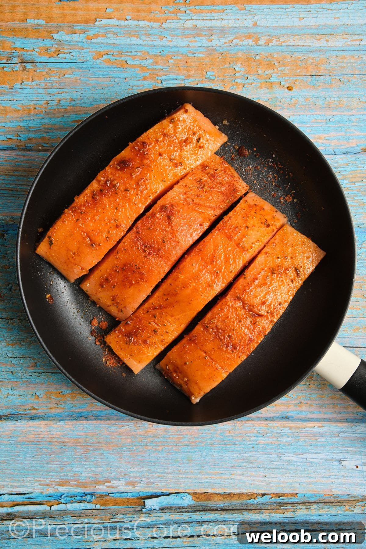 Salmon cooking in a skillet.