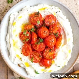 A square image of a ricotta dip in a bowl topped with tomatoes