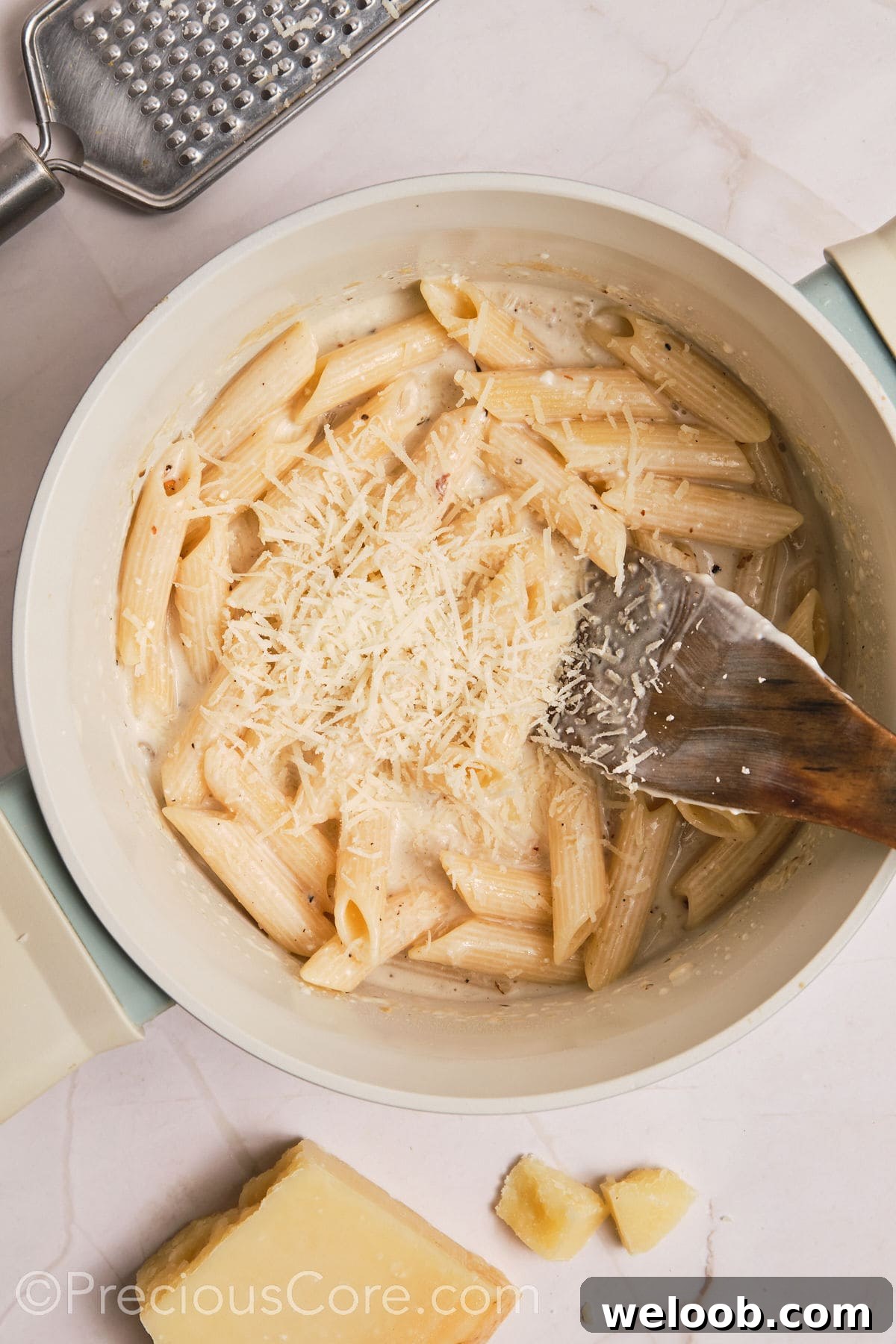 Parmesan added to the pot of creamy pasta.