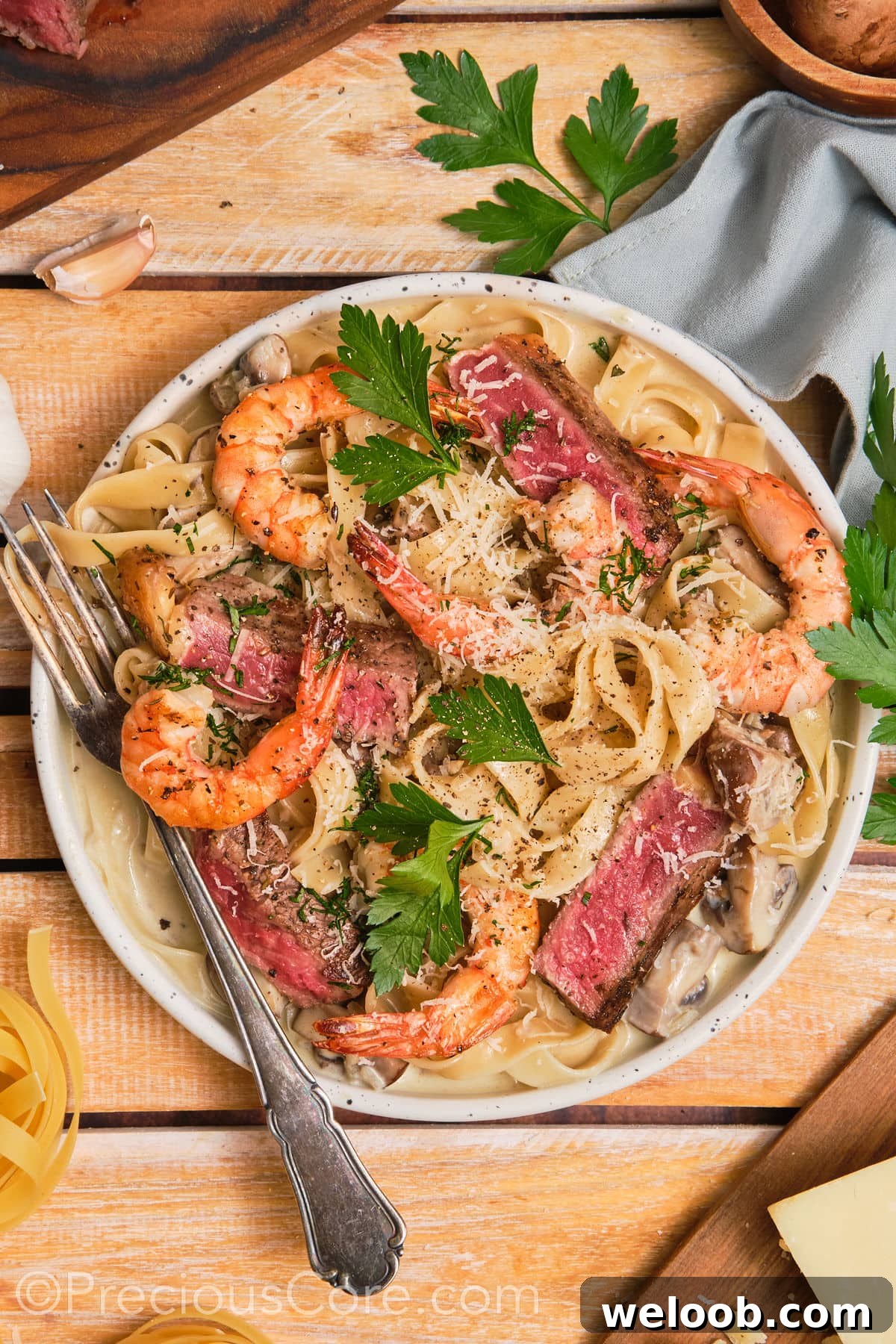 Bowl of steak and shrimp pasta with a fork on the side.