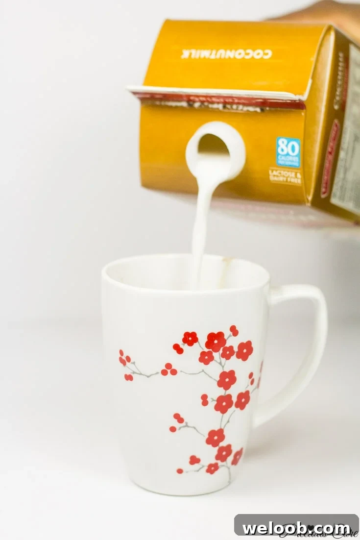 Carton pouring coconut milk into a floral mug.