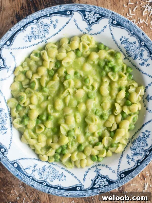 An overhead shot of Pasta and Piselli (peas) in a blue bowl sitting on a wooden surface.