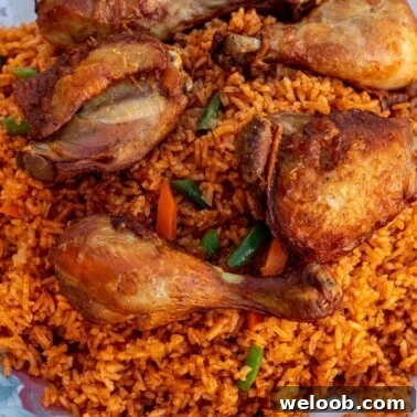 Jollof Rice on a serving platter with cooked chicken thighs and drumsticks on top