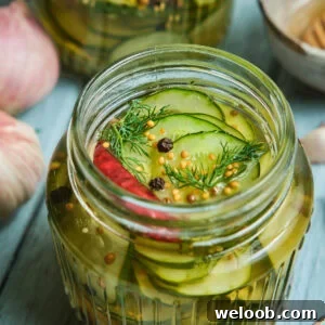 Quick pickled cucumbers in a mason jar with peppercorns on top.