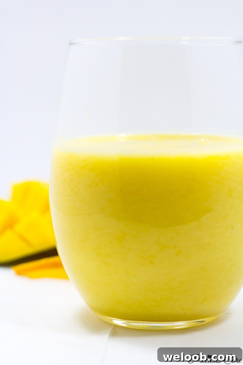 Pineapple mango smoothie in a small glass.