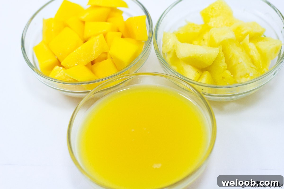Bowls of pineapple, mango, and orange juice.