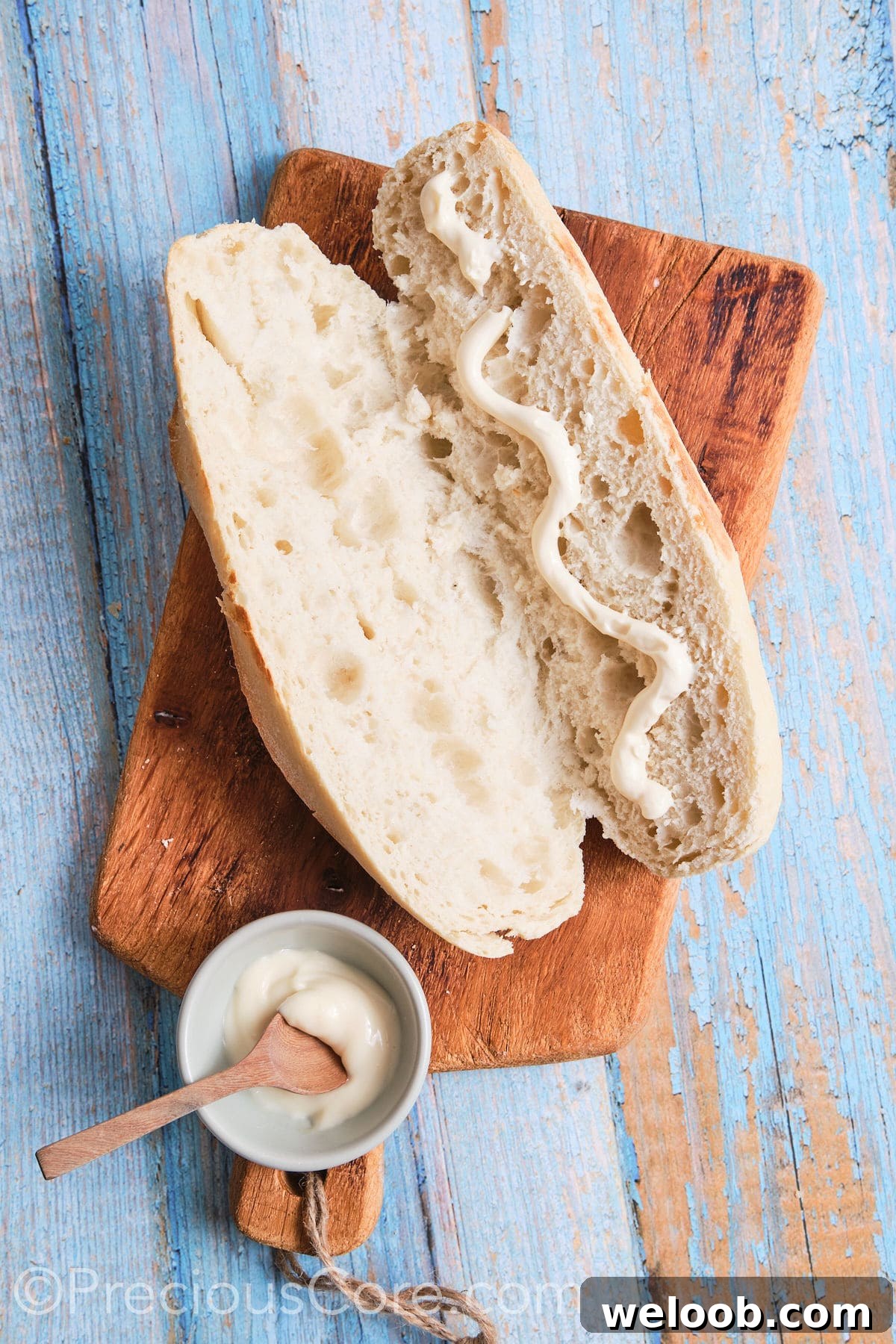Mayonnaise drizzled on one side of a baguette.