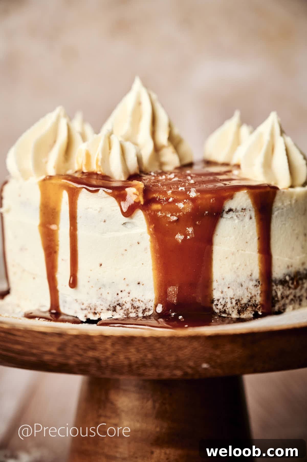 Salted Caramel Cake on a cake stand with caramel dripping down the sides.
