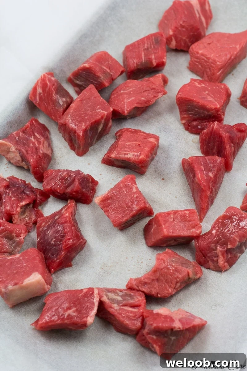 Cubed beef on a lined baking sheet.