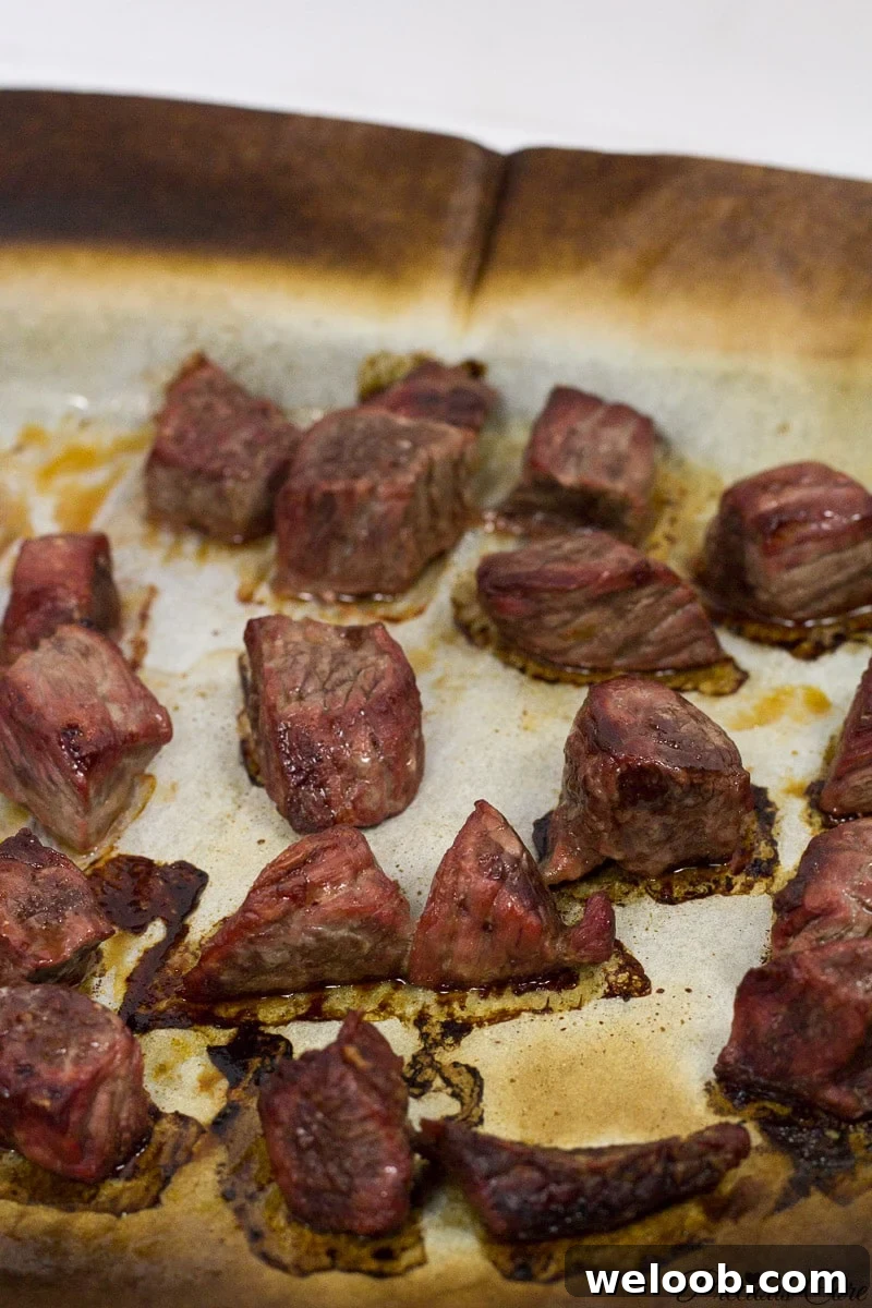 Cooked meat on a lined baking sheet.