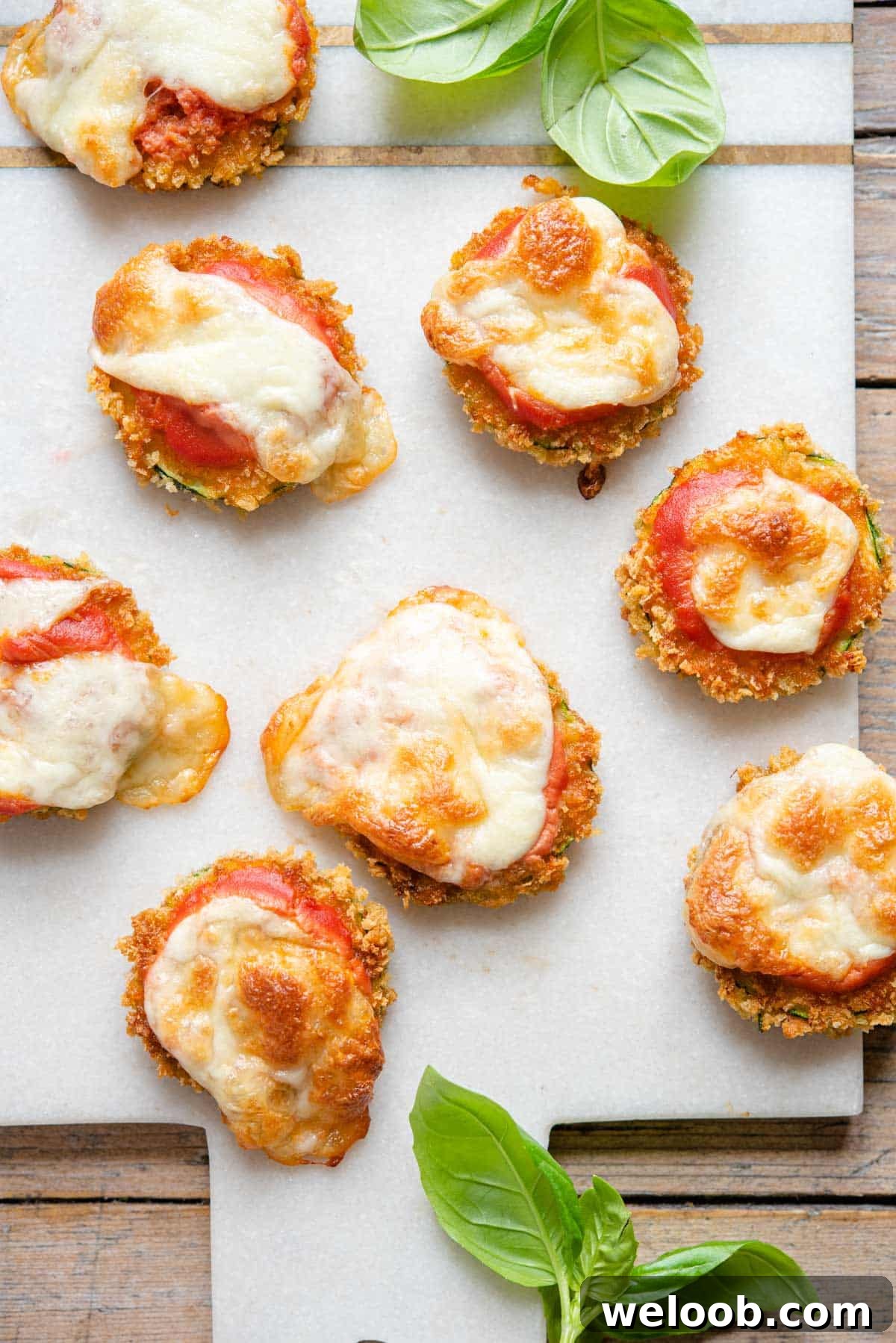 An overhead shot of zucchini pizza bites on a marble cutting board