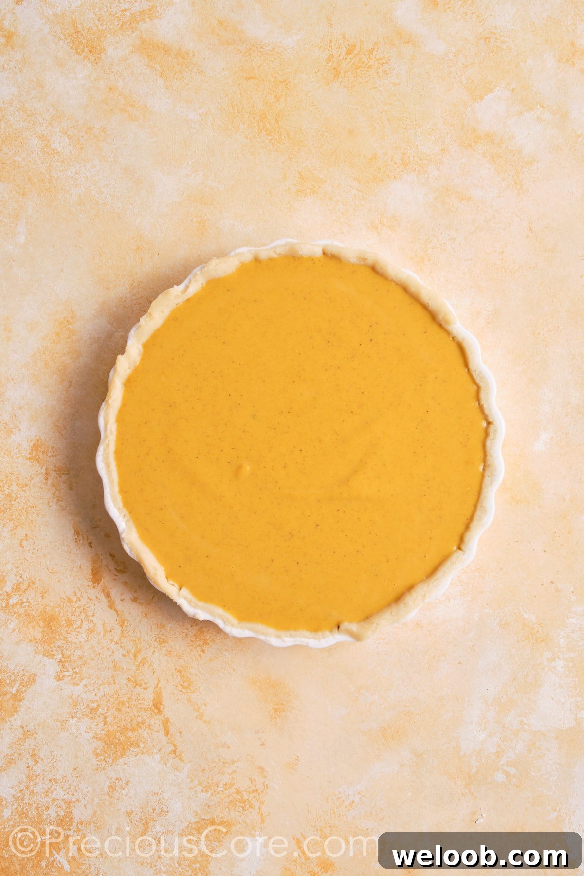 Pumpkin pie filling poured into unbaked pie crust.