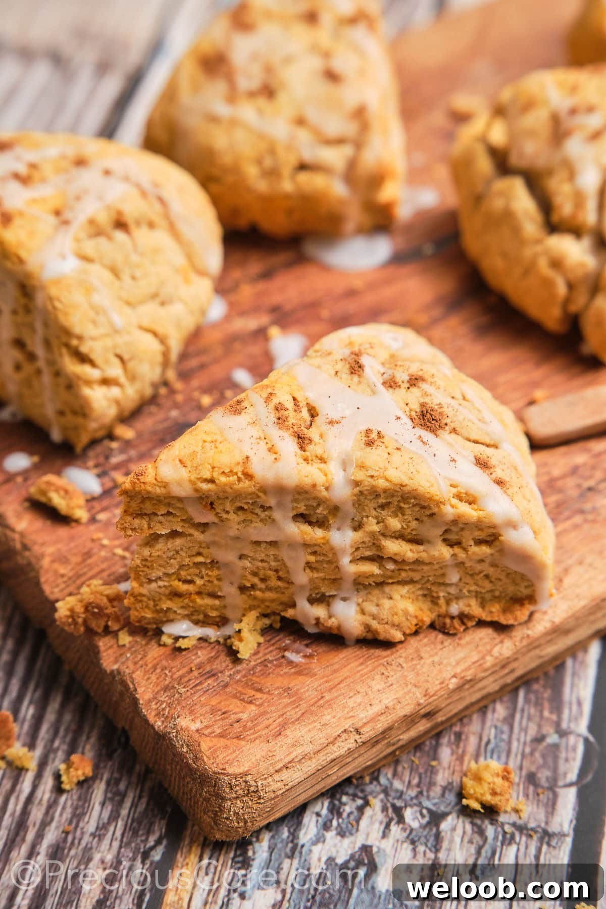 Buttery Sweet Potato Scones with Maple Glaze Recipe 2 A triangle sweet potato scone with a white glaze on top.