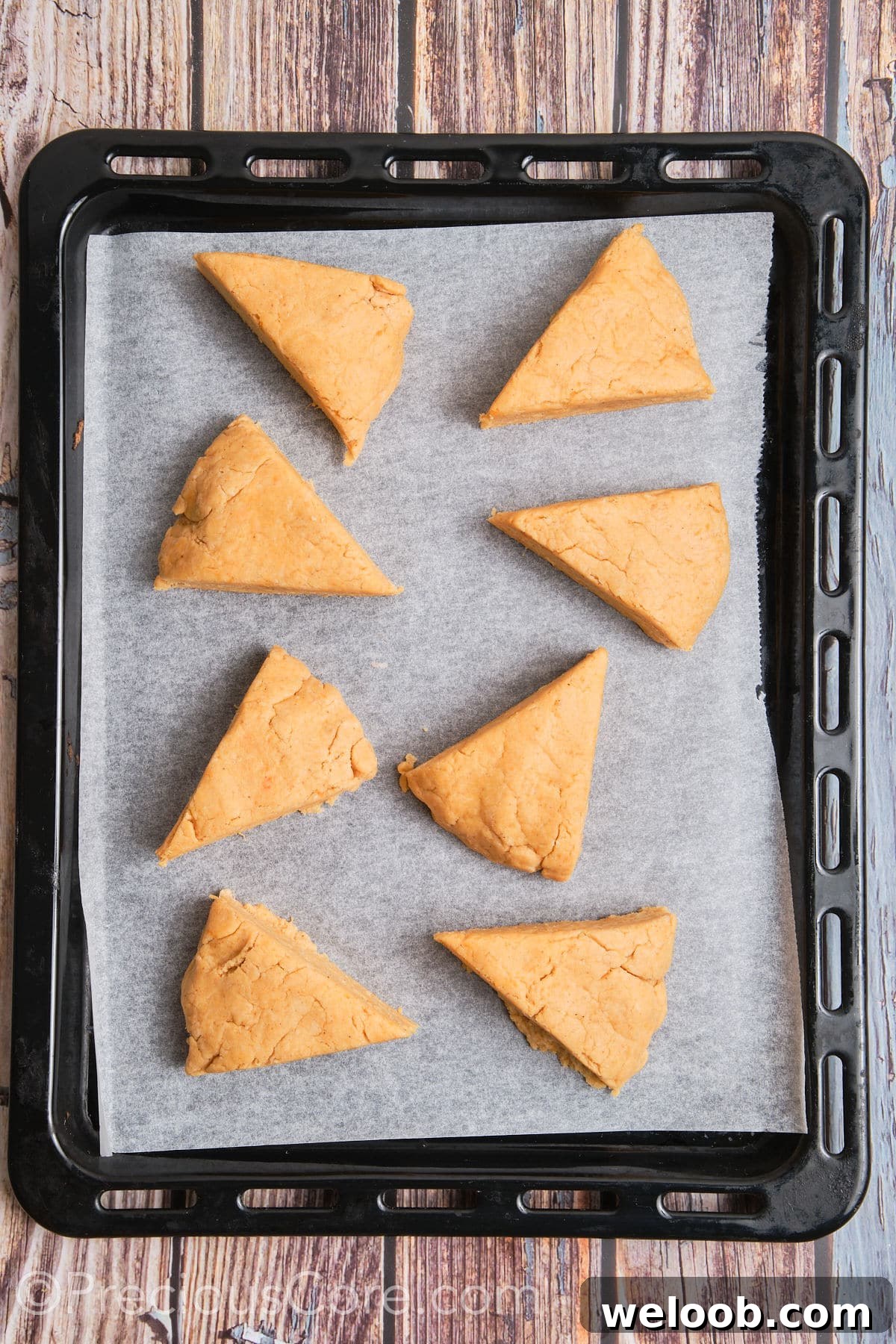 Buttery Sweet Potato Scones with Maple Glaze Recipe 12 Triangles of unbaked scones placed on parchment paper.