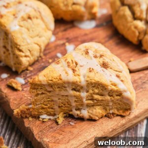 Buttery Sweet Potato Scones with Maple Glaze Recipe 19 A triangle sweet potato scone with a white glaze on top.