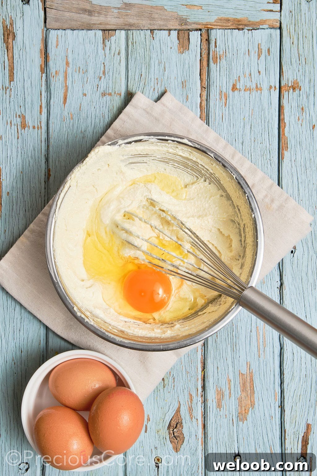 eggs whisked into a creamed butter mixture in a bowl.