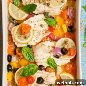 White fish fillets in a casserole dish baked with veggies.