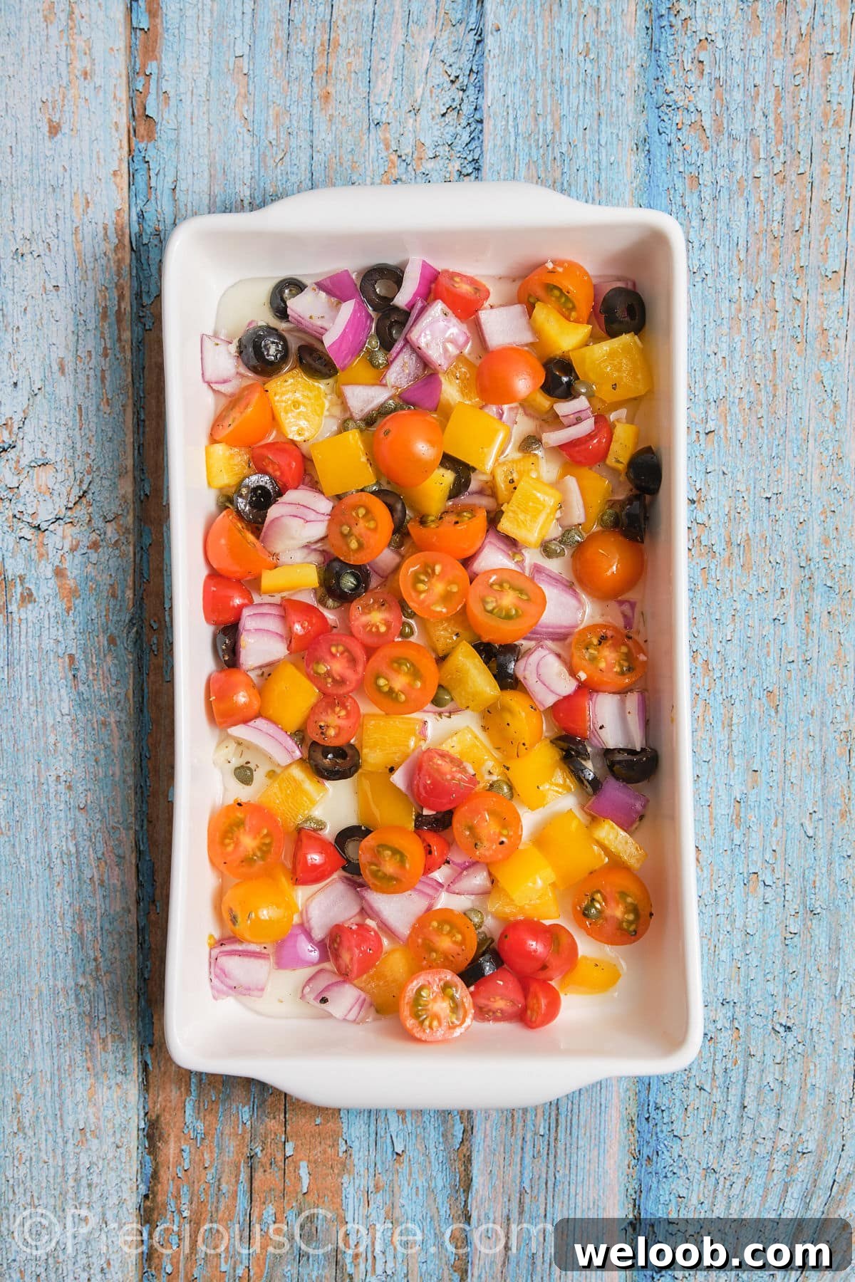 Chopped veggies arranged in a baking dish. 