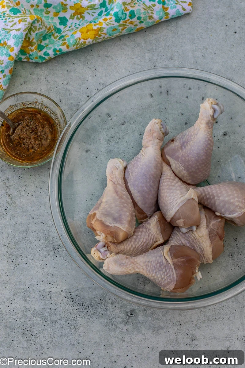 Chicken drumsticks that have been patted dry in a large mixing bowl.