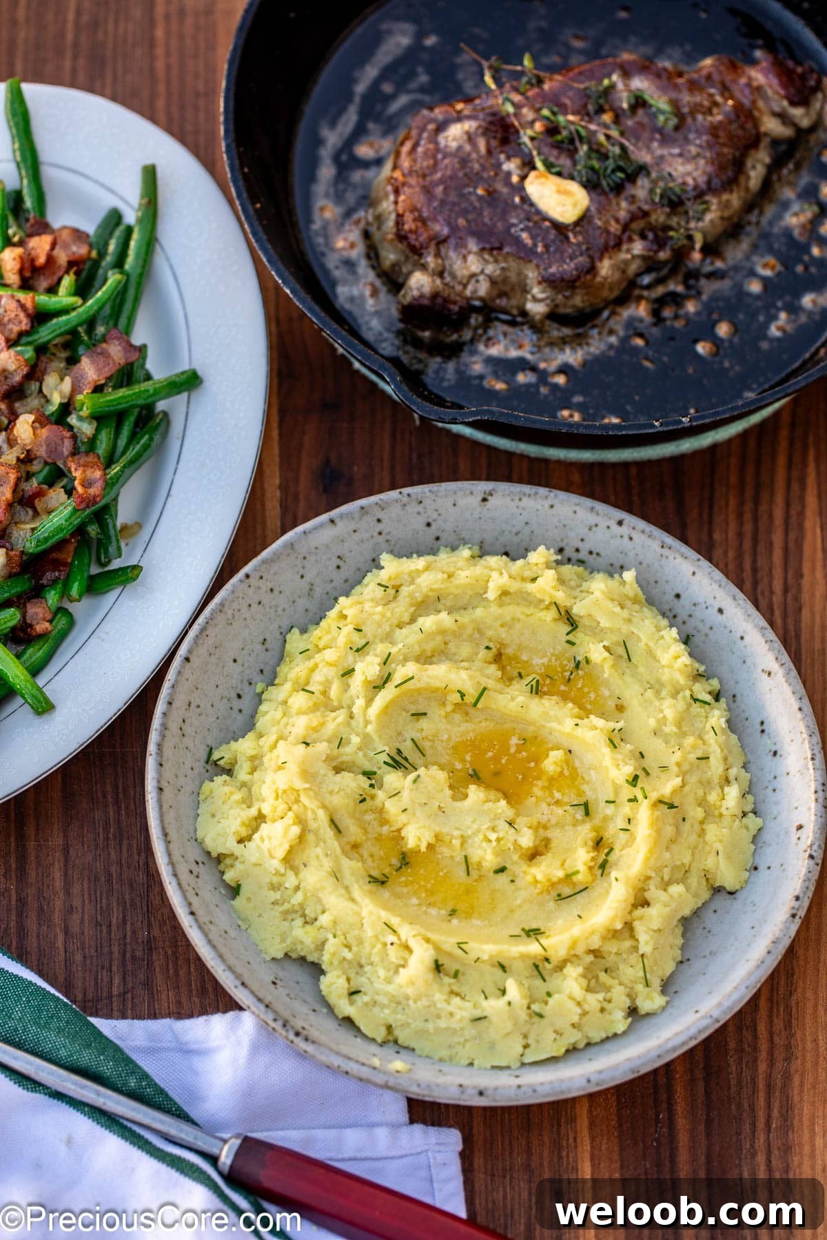 Creamy potatoes in a bowl topped with pools of butter.