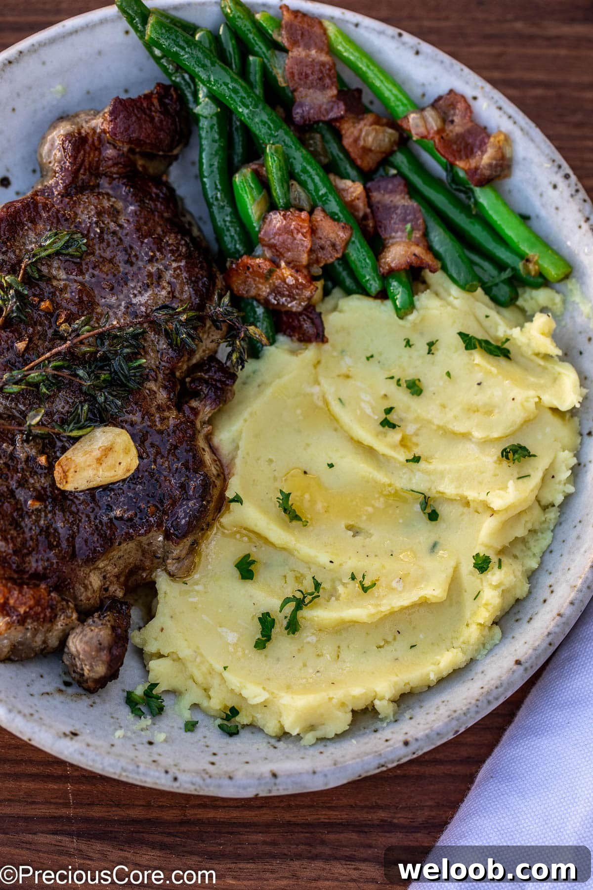 Bowl of steak, bacon green beans, and mashed white sweet potatoes.