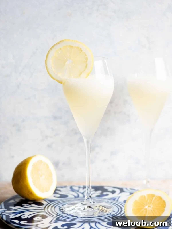 A Sgroppino cocktail in a flute glass with a slice of lemon on the side.