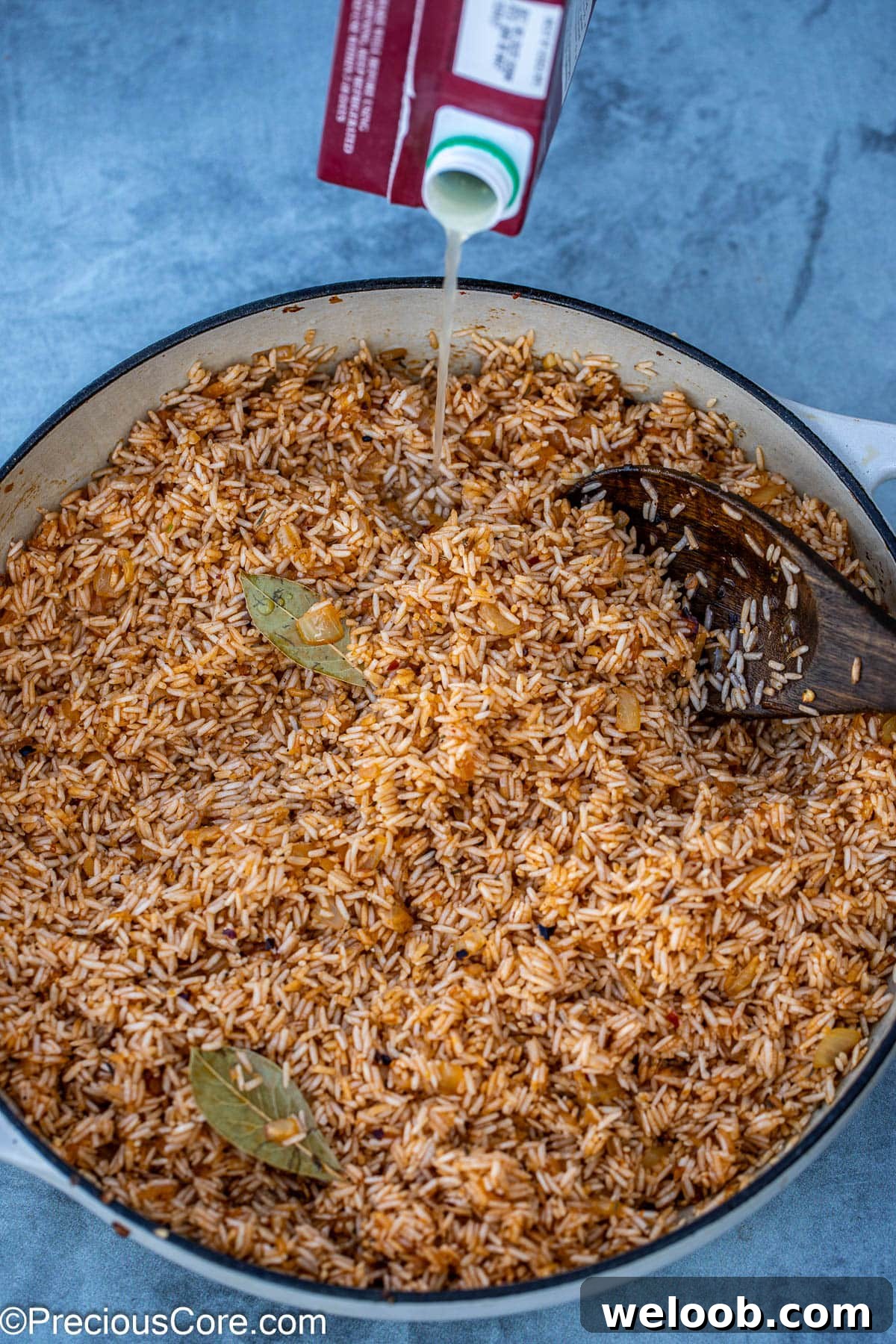 adding chicken broth to the rice.
