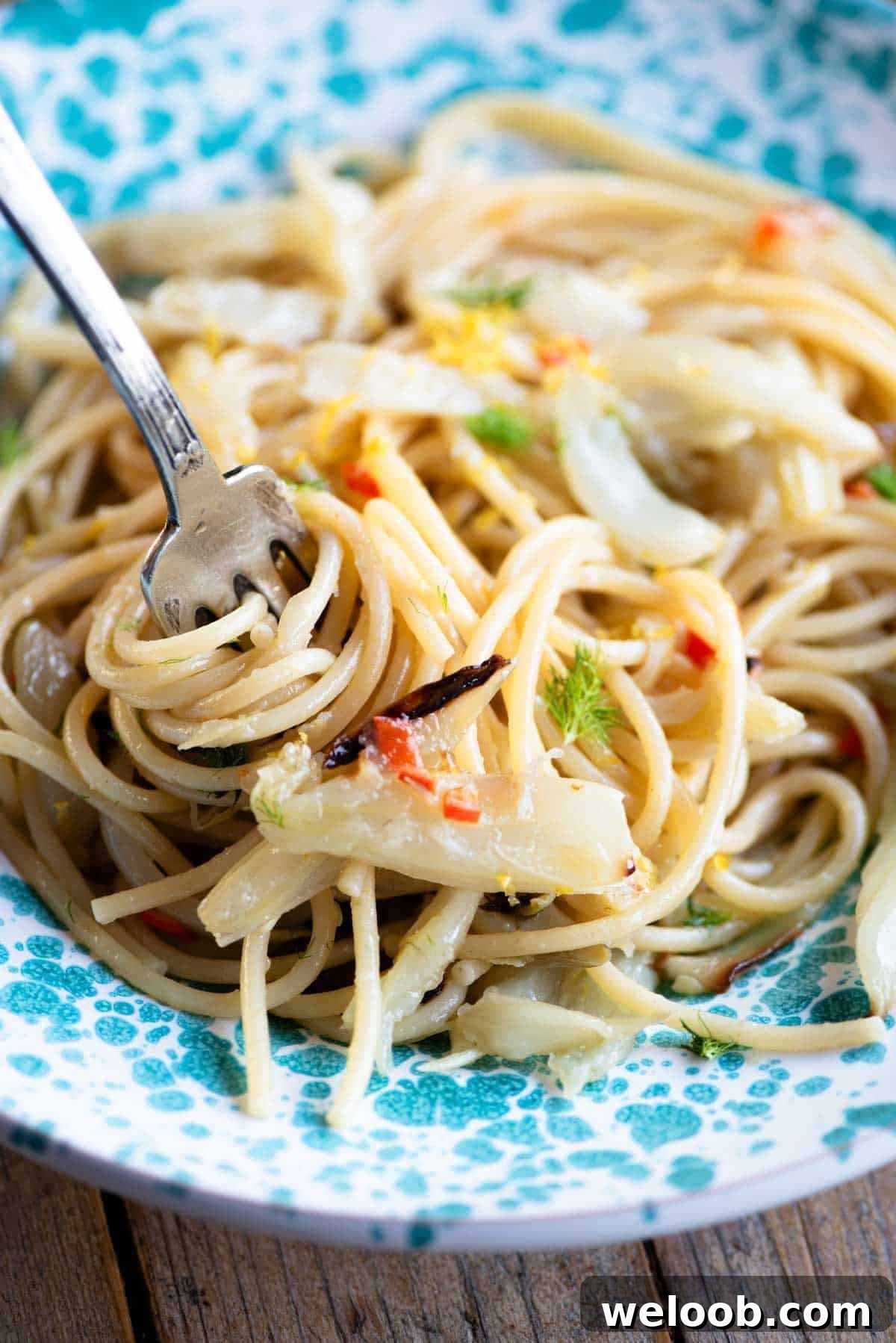 A close up of roasted fennel spaghetti in a bowl twirled around a fork.