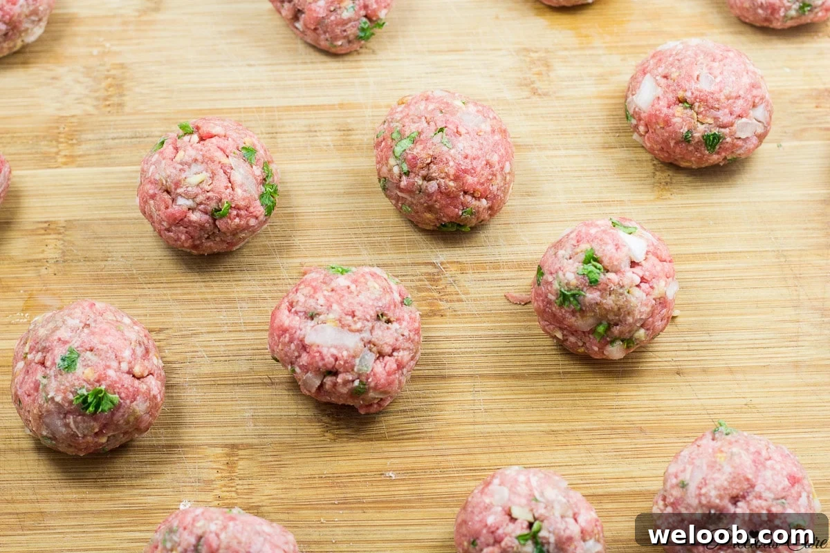 Raw meatballs on a wooden cutting board.