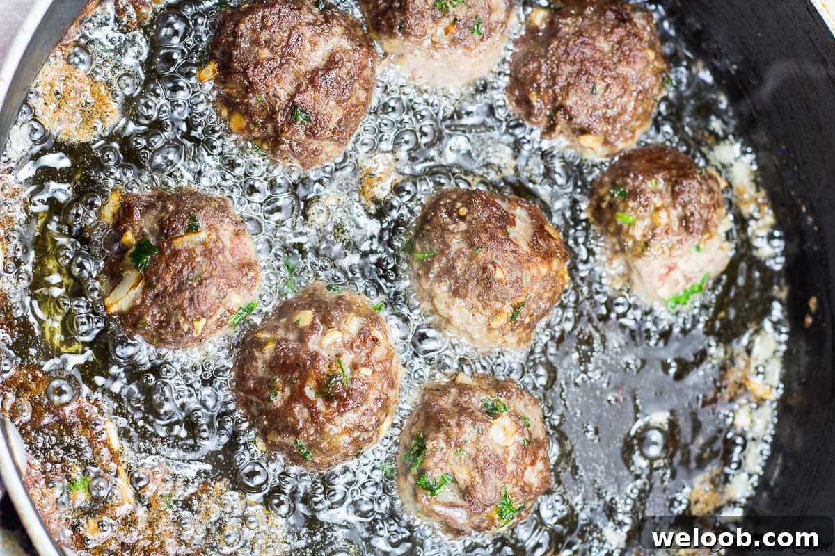 Meatballs frying in a pan.