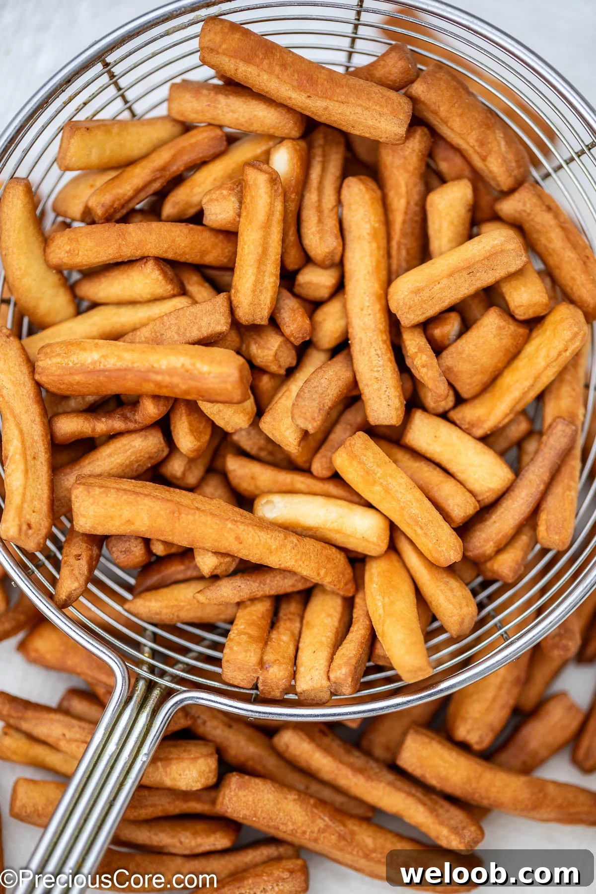 Golden brown fried chin chin in frying spoon.
