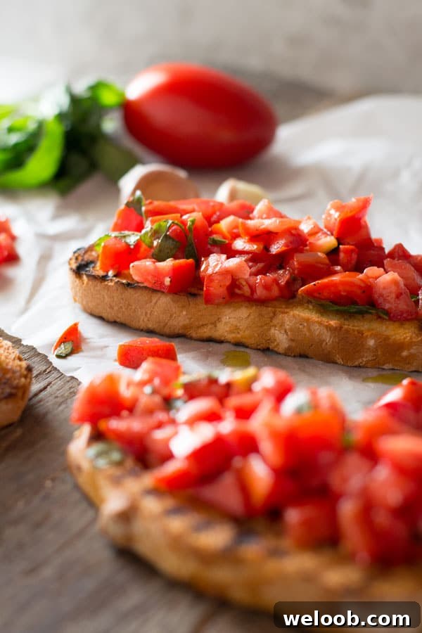 A close up of chopped fresh tomatoes on toasted garlic bread sitting on a wooden board