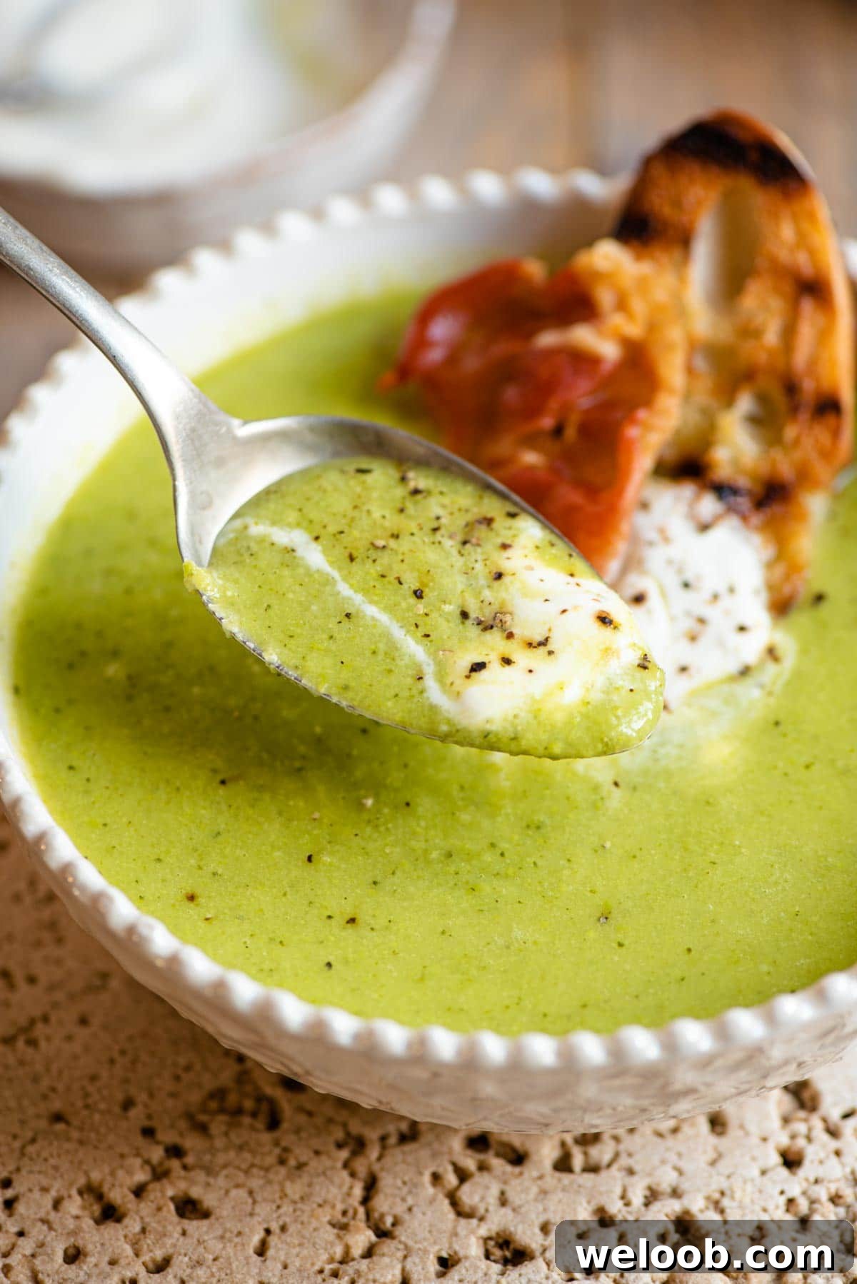 A close up of a spoonful of green pea soup