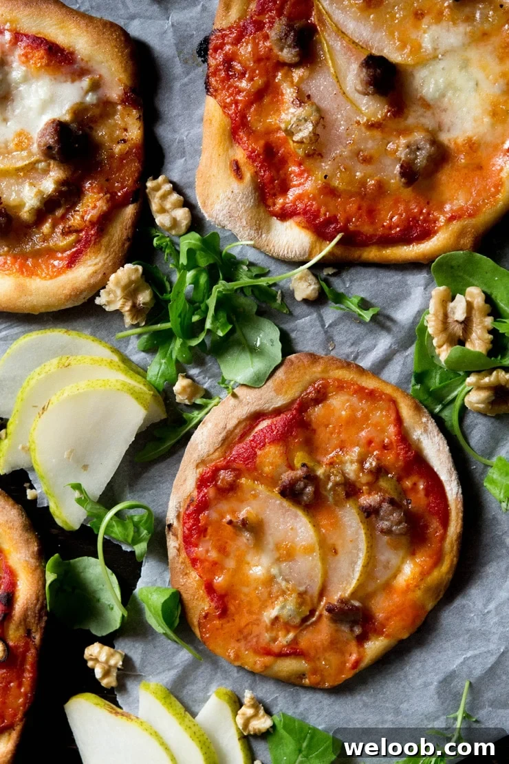 An overhead photo of mini sausage pizzas with pear, gorgonzola and arugula