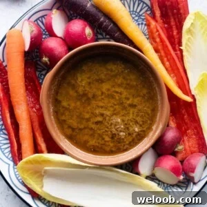 Bagna Cauda in a terracotta dish with raw vegetables all around.