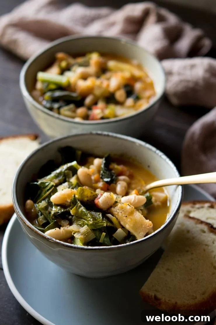 close up of a bowl of Tuscan vegetable soup another bowl with bread in back ground