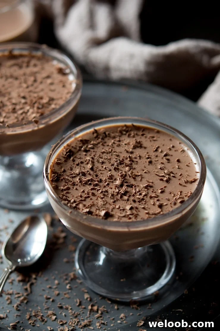 Close up of chocolate panna cotta in a glass bowl topped with grated chocolate.