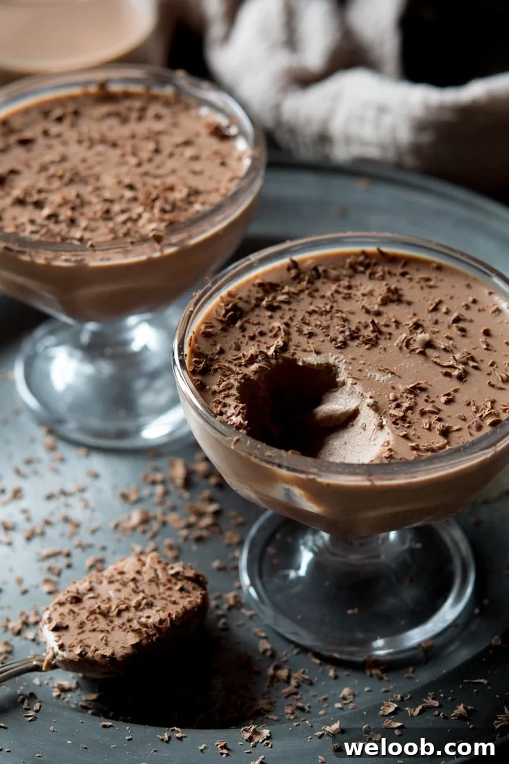 A close up of chocolate panna cotta with a spoonful of panna cotta in the background