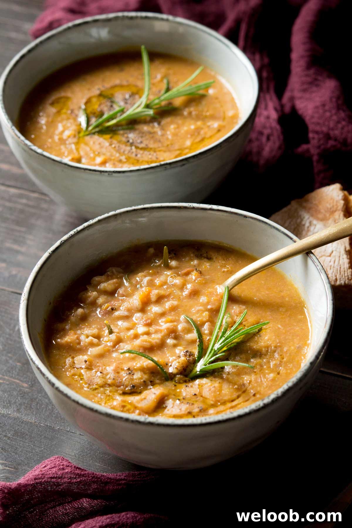 Tuscan farro soup in a bowl with a spoon and rosemary