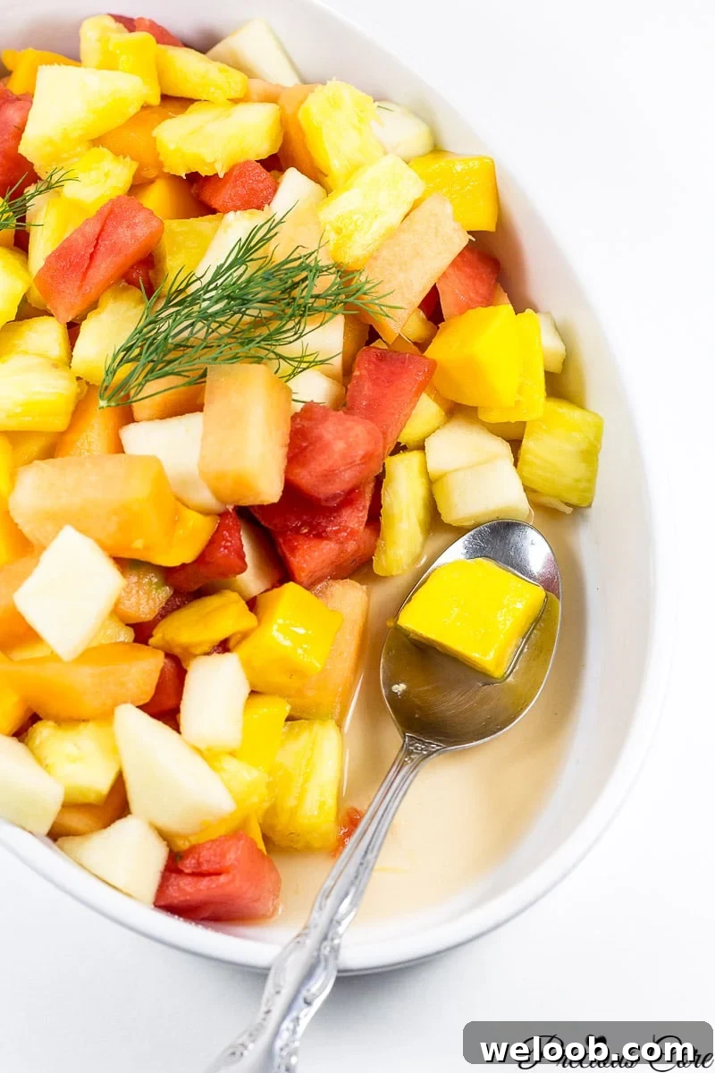Spoon scooping fruit salad from a serving bowl.