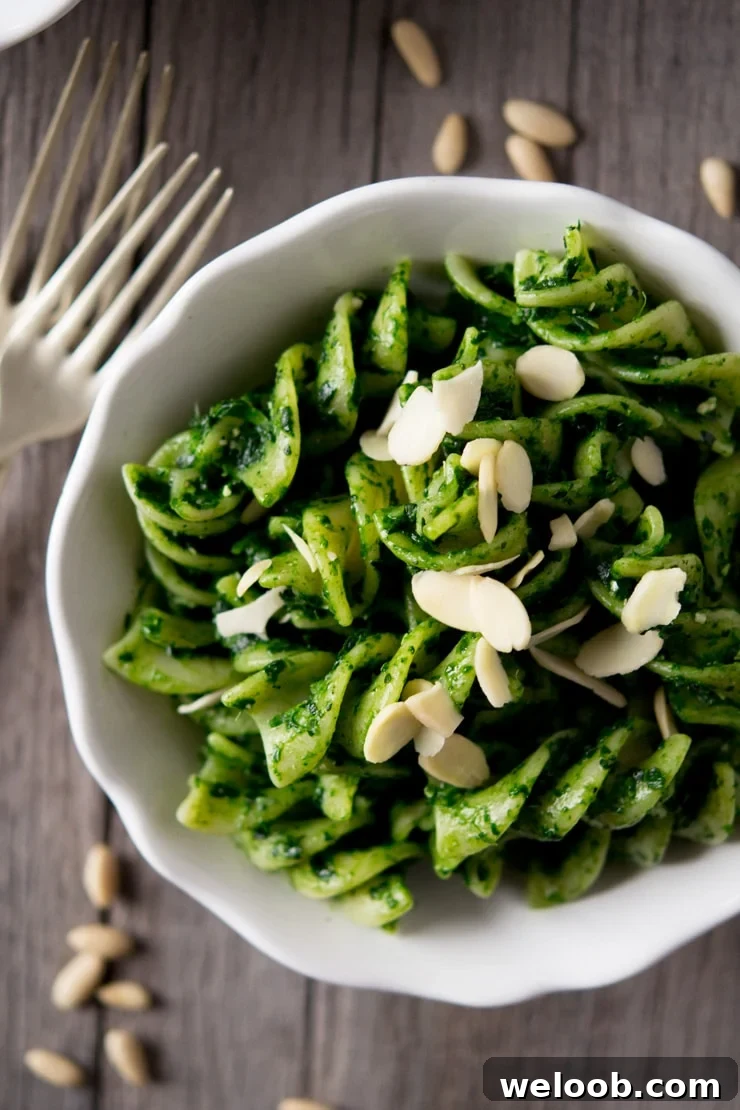 A close up of pesto pasta sauce with fusilli pasta in a white bowl