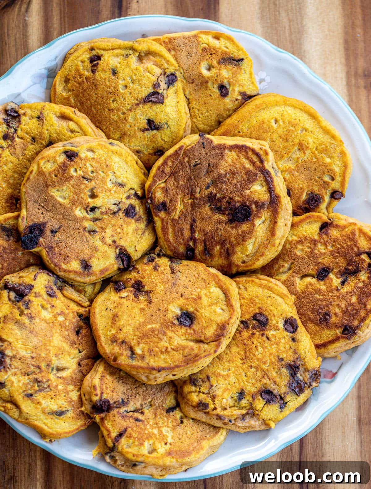 A round tray with loads of pancakes with chocolate chips.