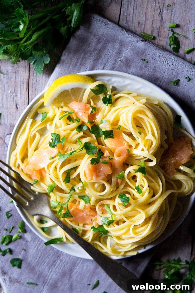 a close up of smoked salmon pasta on a plate and sitting on a wooden surface