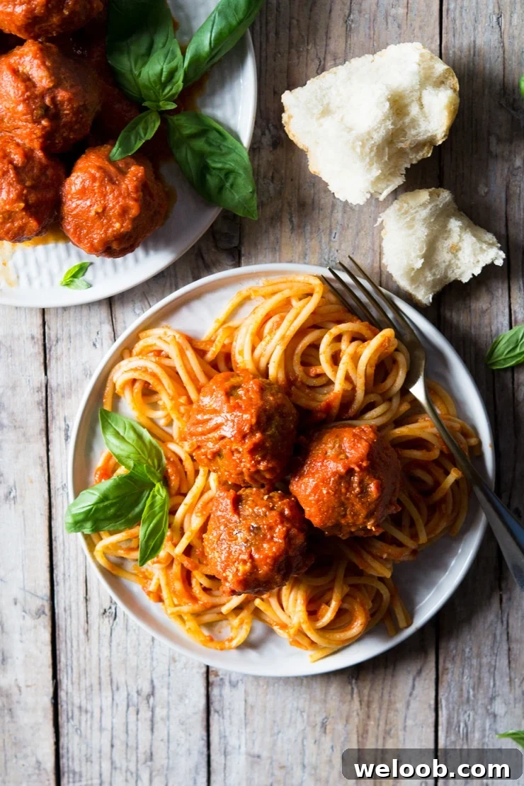 An overhead shot of mozzarella stuffed meatballs and spaghetti on a wooden surface with torn bread