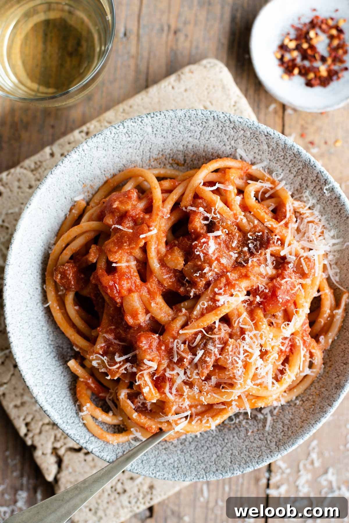 An overhead shot of a bowl of Bucatini all'Amatriciana topped with pecorino cheese