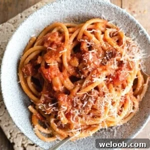 A close up of bucatini pasta in a bowl with amatriciana sauce